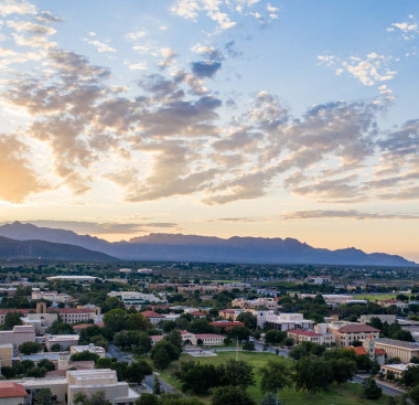 A picture with some clouds, mountains, and buildings